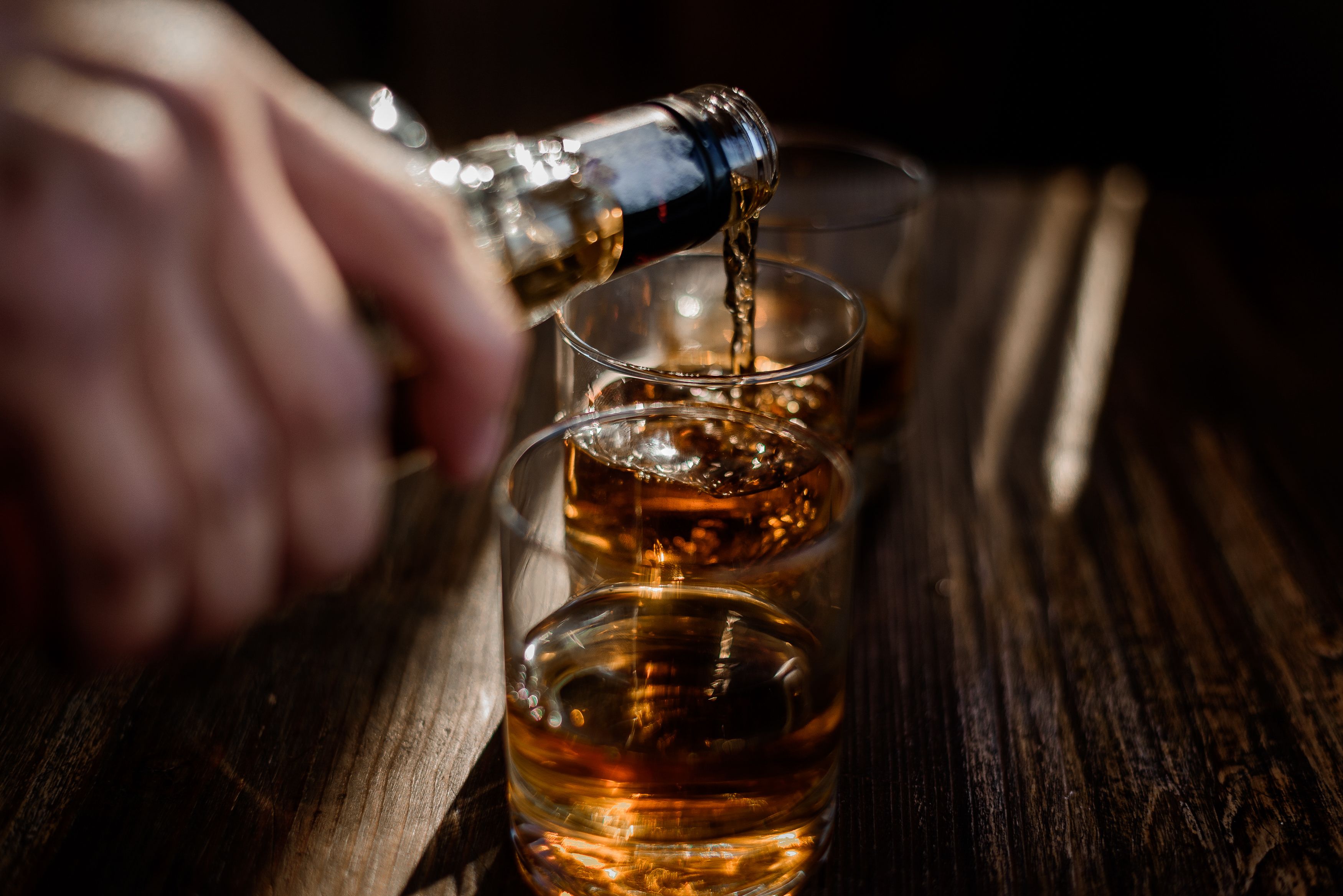 pouring-strong-alcohol-drink-into-glasses-which-are-wooden-table.jpg
