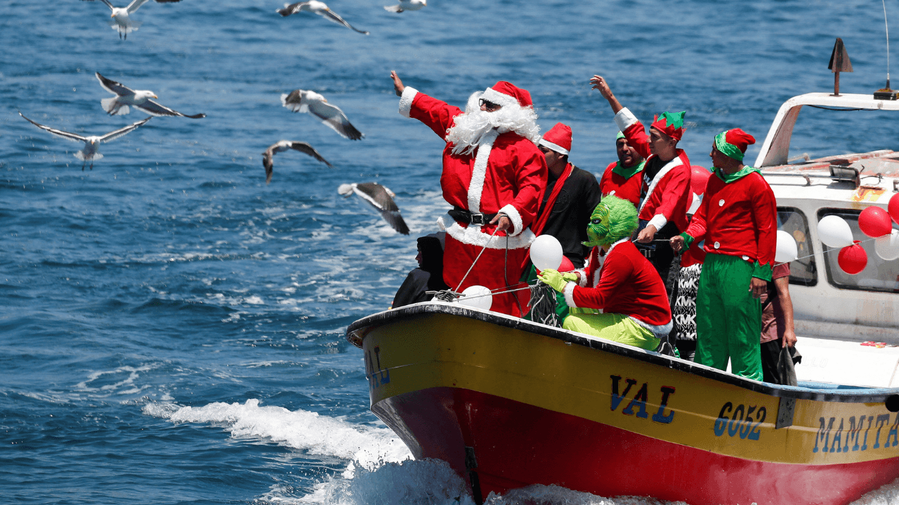 Un hombre vestido de Papá Noel saluda a la gente desde un barco de pescadores en la víspera de Navidad en la costa de Valparaíso, Chile